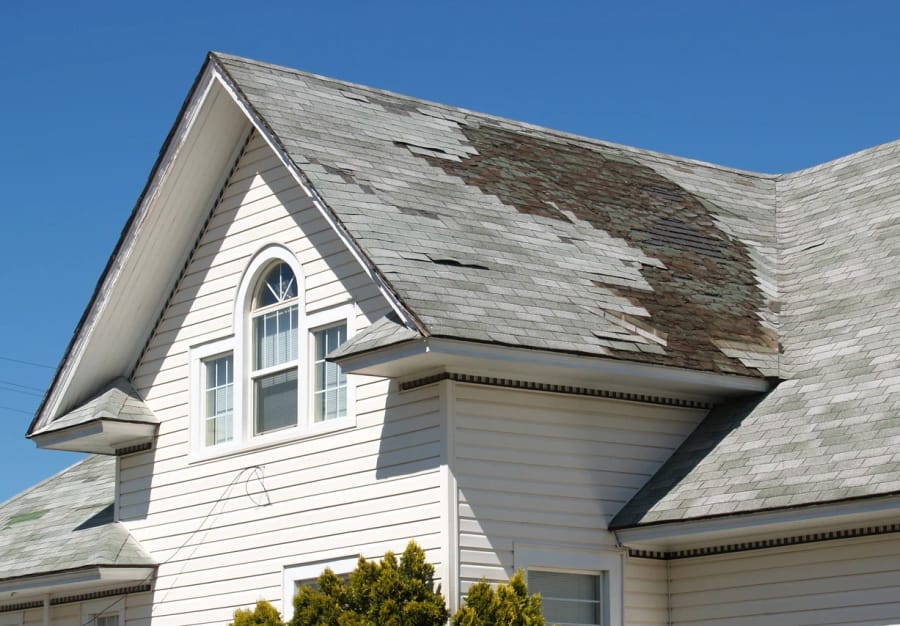 Roofing specialist inspecting storm-damaged shingles on a Linn County, OR family home using advanced diagnostic tools